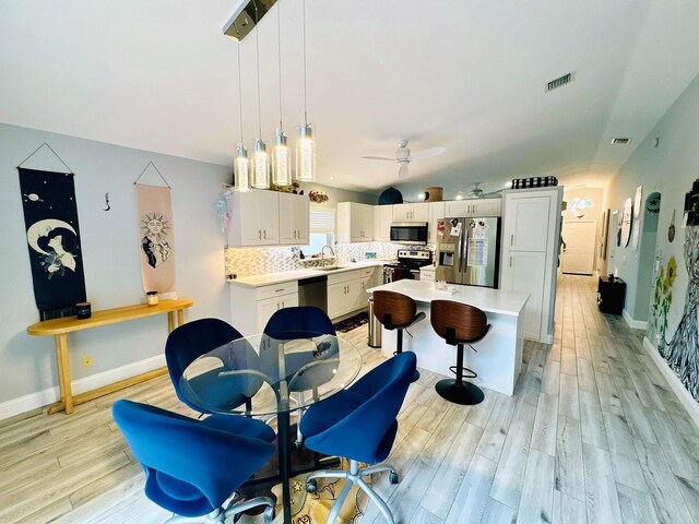 dining space featuring light wood-type flooring, ceiling fan, and sink