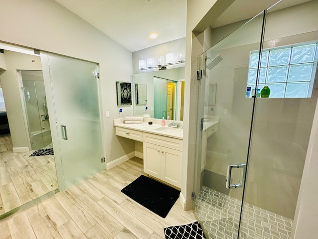 bathroom with vaulted ceiling, vanity, a shower with shower door, and hardwood / wood-style floors