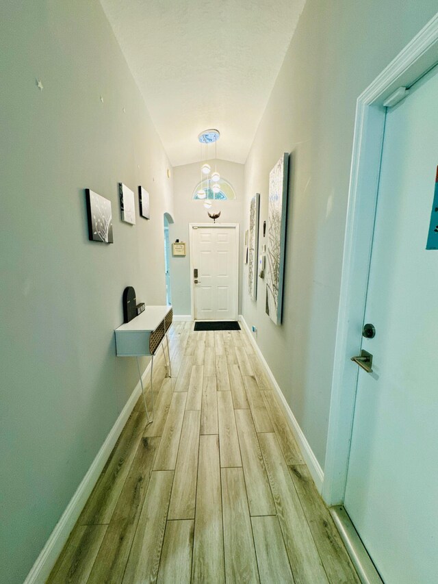 doorway with lofted ceiling and light hardwood / wood-style floors