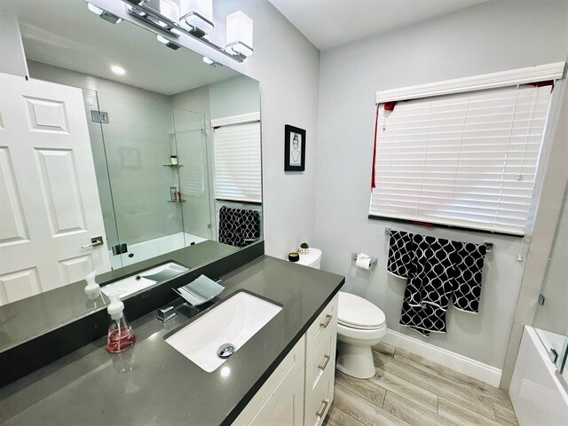 full bathroom featuring wood-type flooring, vanity, plus walk in shower, and toilet