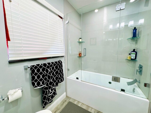 bathroom featuring wood-type flooring and combined bath / shower with glass door