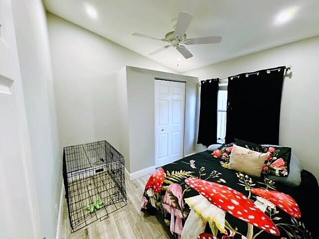 bedroom with lofted ceiling, a closet, light hardwood / wood-style floors, and ceiling fan