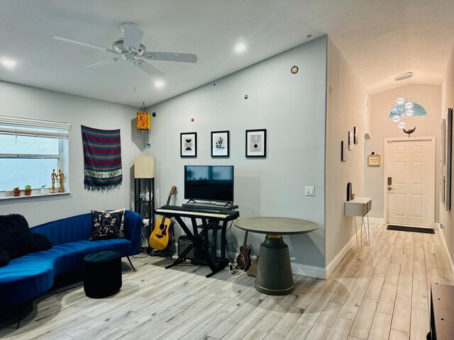 living room with ceiling fan, vaulted ceiling, and light hardwood / wood-style floors