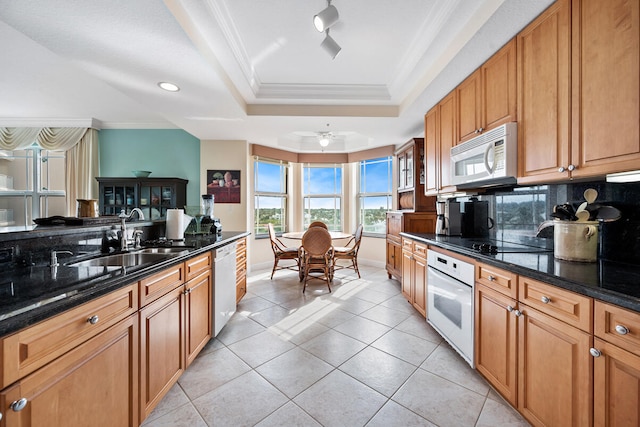 kitchen with dark stone countertops, a tray ceiling, ornamental molding, and white appliances