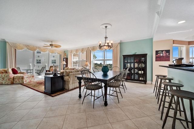 dining space featuring light tile patterned flooring, ceiling fan with notable chandelier, crown molding, and a wealth of natural light