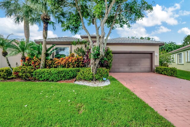 ranch-style house featuring stucco siding, decorative driveway, and a front yard