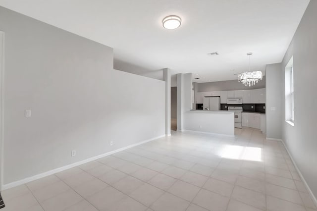 unfurnished living room with an inviting chandelier and light tile patterned floors