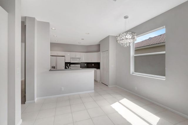 kitchen featuring white cabinets, kitchen peninsula, light tile patterned floors, white appliances, and a notable chandelier