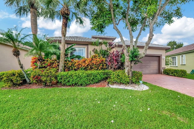 mediterranean / spanish-style home featuring a front yard, driveway, an attached garage, stucco siding, and a tiled roof