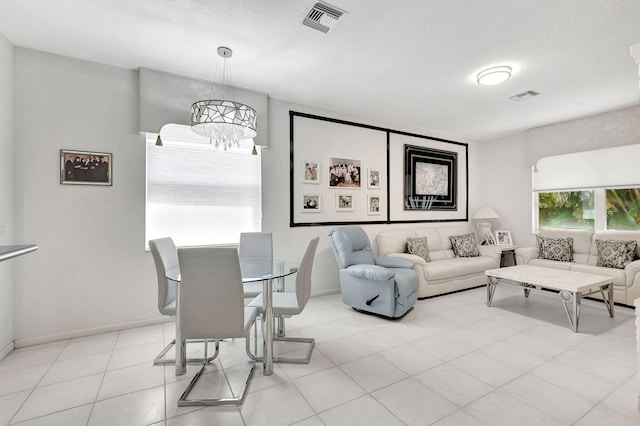 living room featuring a notable chandelier, light tile patterned floors, and a textured ceiling