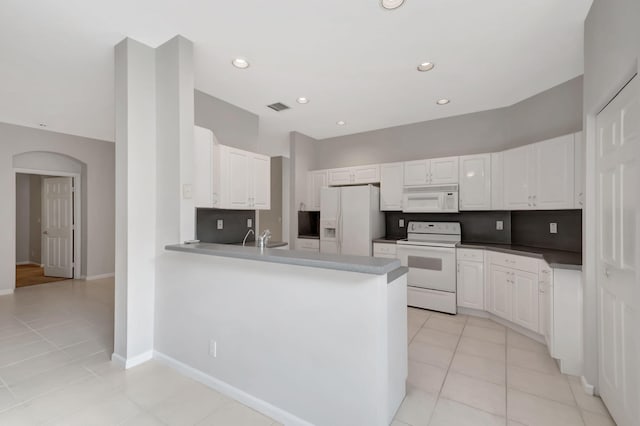 kitchen with kitchen peninsula, white appliances, and white cabinetry