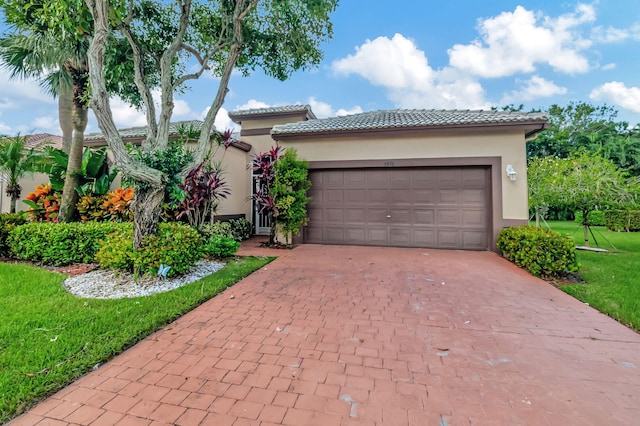 view of front of home with an attached garage, stucco siding, a front lawn, a tiled roof, and decorative driveway