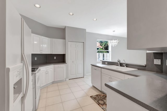 kitchen with white cabinets, light tile patterned floors, sink, white appliances, and decorative light fixtures