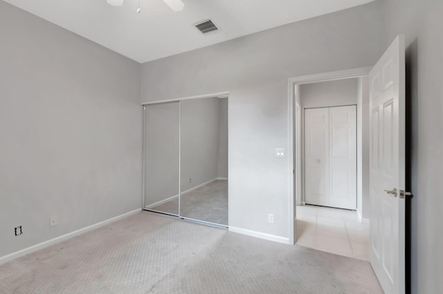 unfurnished bedroom with a closet, light colored carpet, and ceiling fan