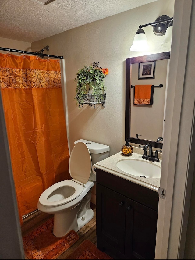 bathroom featuring vanity, a textured ceiling, wood-type flooring, a shower with shower curtain, and toilet