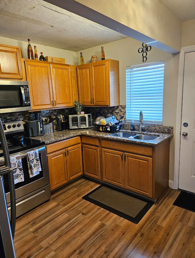 kitchen featuring appliances with stainless steel finishes, tasteful backsplash, dark wood-type flooring, and sink