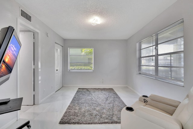 hallway featuring light tile patterned flooring and a textured ceiling