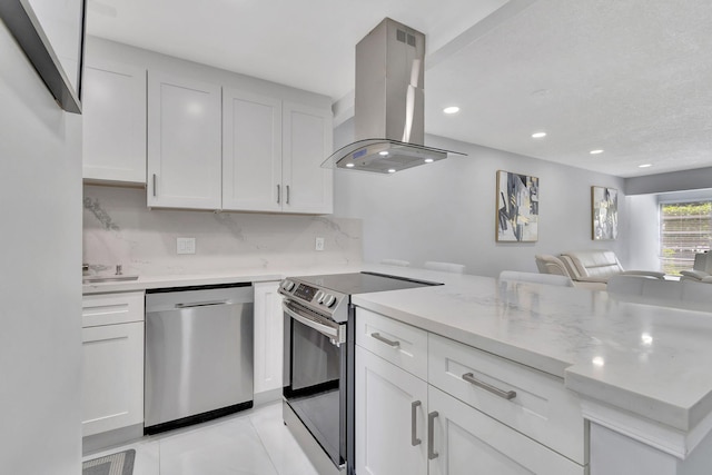 kitchen featuring island exhaust hood, decorative backsplash, light stone counters, stainless steel appliances, and white cabinets