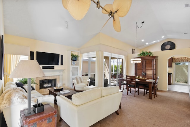 carpeted living room with ceiling fan, lofted ceiling, and a tile fireplace