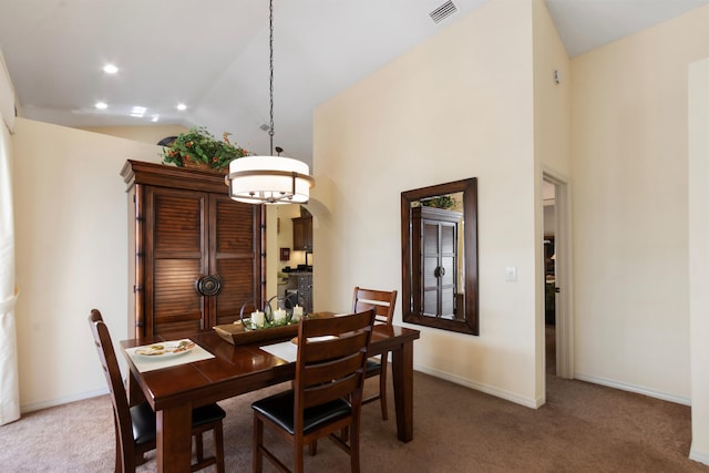 carpeted dining space featuring high vaulted ceiling and a notable chandelier