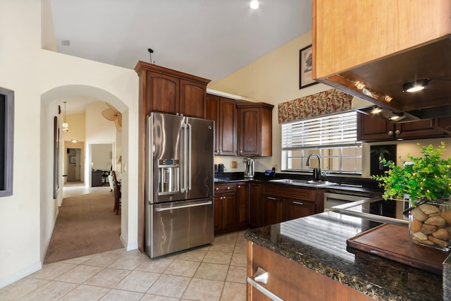 kitchen with high end refrigerator, sink, light tile patterned floors, and dark stone counters