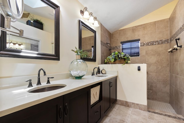 bathroom with tile patterned floors, vanity, tiled shower, and vaulted ceiling