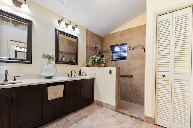 bathroom with a tile shower, tile patterned flooring, a textured ceiling, lofted ceiling, and vanity