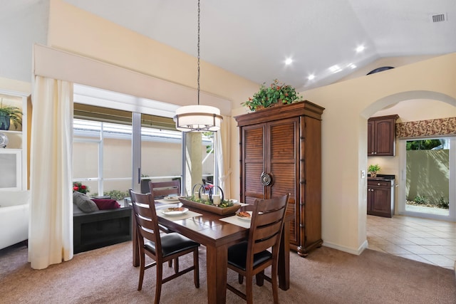 dining area featuring an inviting chandelier, light colored carpet, and vaulted ceiling