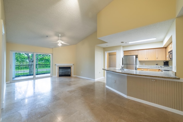 unfurnished living room with a textured ceiling, ceiling fan, and sink