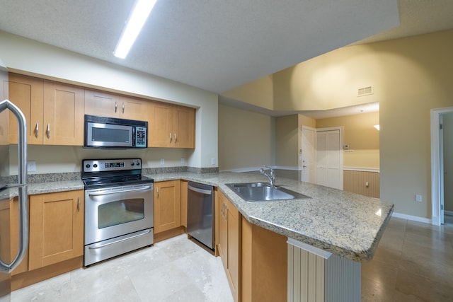 kitchen featuring light stone counters, a textured ceiling, sink, kitchen peninsula, and appliances with stainless steel finishes