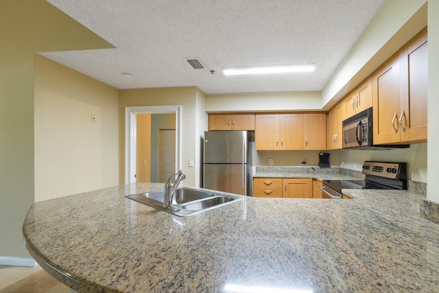 kitchen with stainless steel appliances, kitchen peninsula, a textured ceiling, and sink