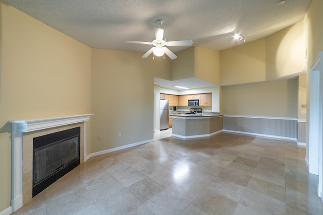 unfurnished living room with a towering ceiling, ceiling fan, and a textured ceiling