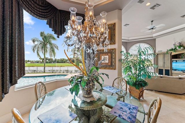 dining area featuring ceiling fan with notable chandelier, a water view, crown molding, and a tray ceiling