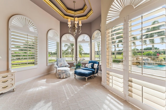 sitting room featuring a raised ceiling, ornamental molding, carpet floors, and an inviting chandelier