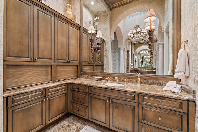 bathroom with a notable chandelier, ornamental molding, and vanity