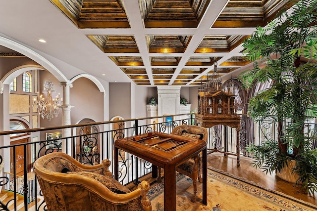 interior space with decorative columns, coffered ceiling, ornamental molding, beamed ceiling, and a chandelier