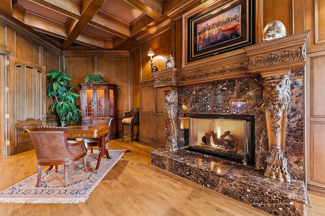 office featuring ornamental molding, beam ceiling, light hardwood / wood-style flooring, a premium fireplace, and wood walls