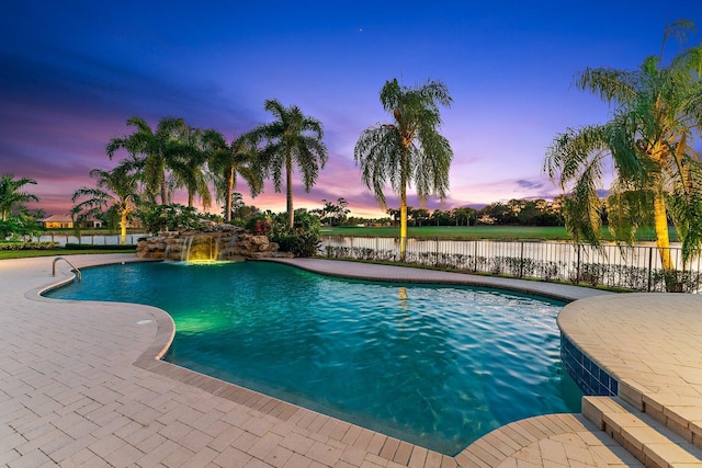 pool at dusk featuring a patio area and pool water feature