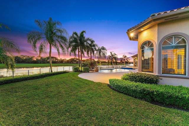 yard at dusk featuring a fenced in pool