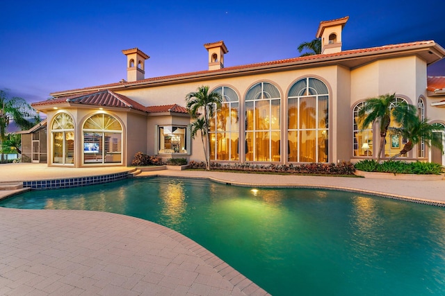 pool at dusk featuring a patio area