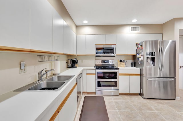 kitchen featuring white cabinetry, sink, light tile patterned floors, and stainless steel appliances