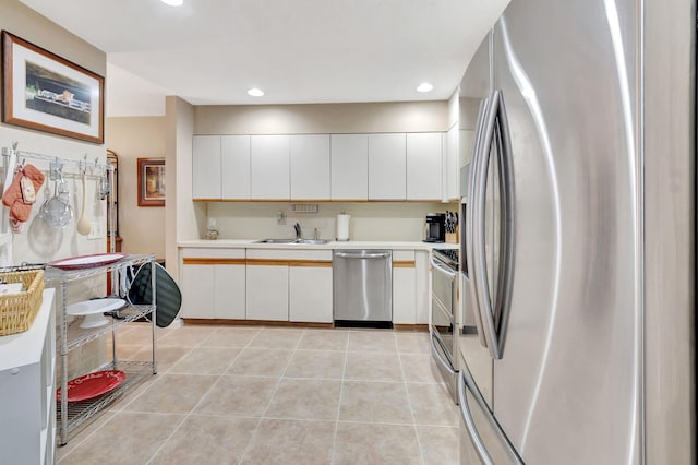 kitchen featuring appliances with stainless steel finishes, light tile patterned flooring, and white cabinetry