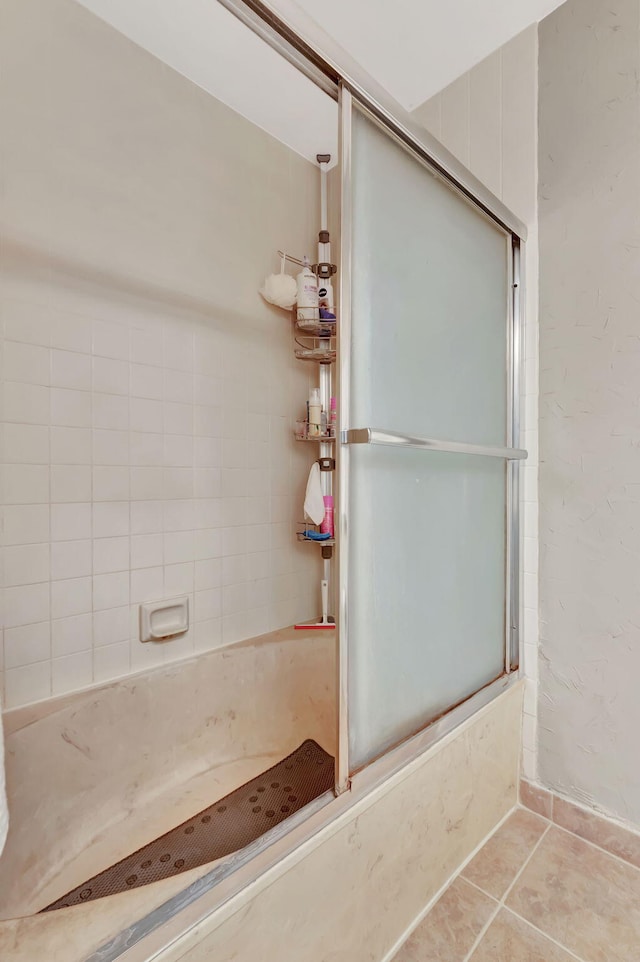 bathroom with combined bath / shower with glass door and tile patterned floors