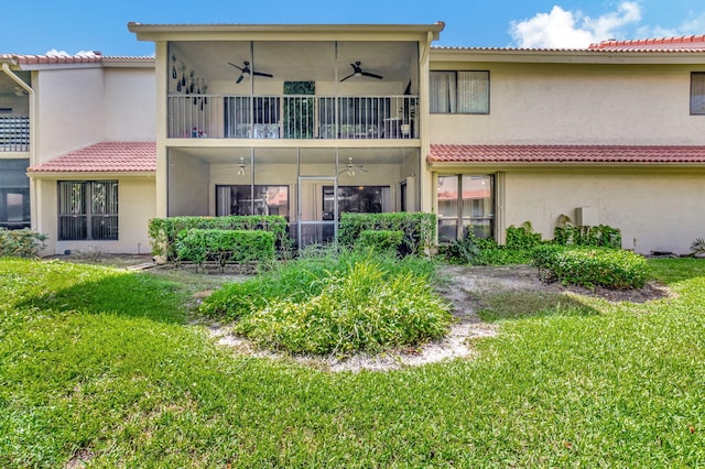 rear view of property featuring a lawn, a balcony, and ceiling fan