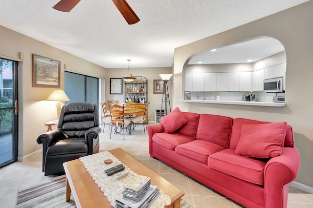 tiled living room with a textured ceiling and ceiling fan