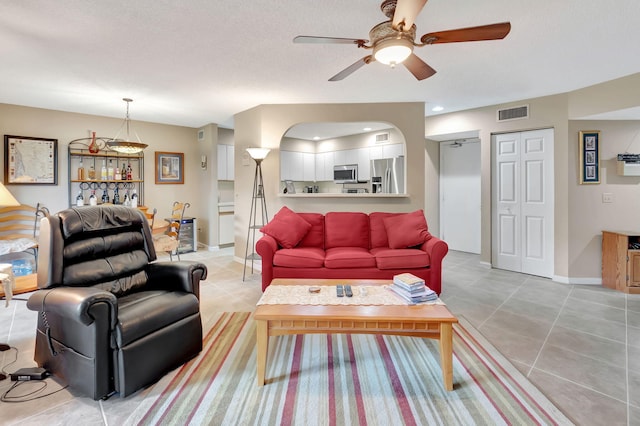 living room featuring ceiling fan, light tile patterned flooring, and a textured ceiling