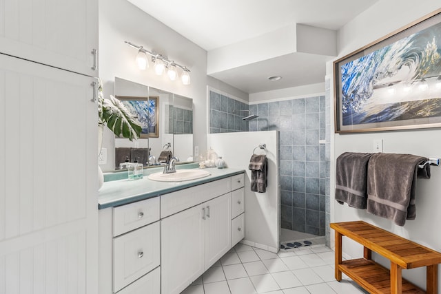 bathroom with tile patterned flooring, vanity, and a tile shower