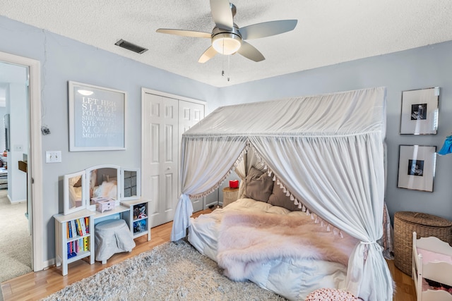 bedroom with a textured ceiling, hardwood / wood-style floors, ceiling fan, and a closet