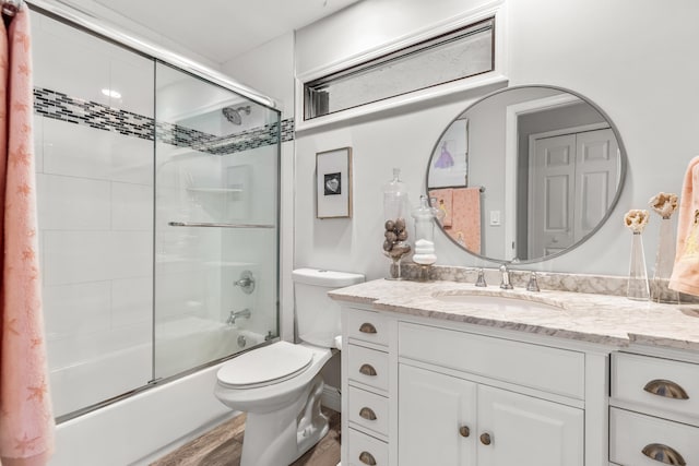 full bathroom with wood-type flooring, combined bath / shower with glass door, toilet, and vanity