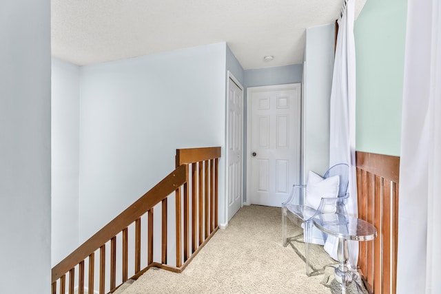 hall featuring a textured ceiling and carpet floors